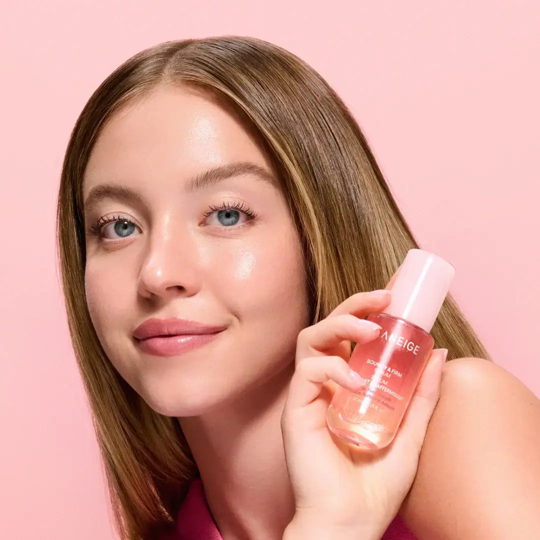 Person holding LANEIGE NEW Bouncy & Firm Serum 30ml with a pink background.