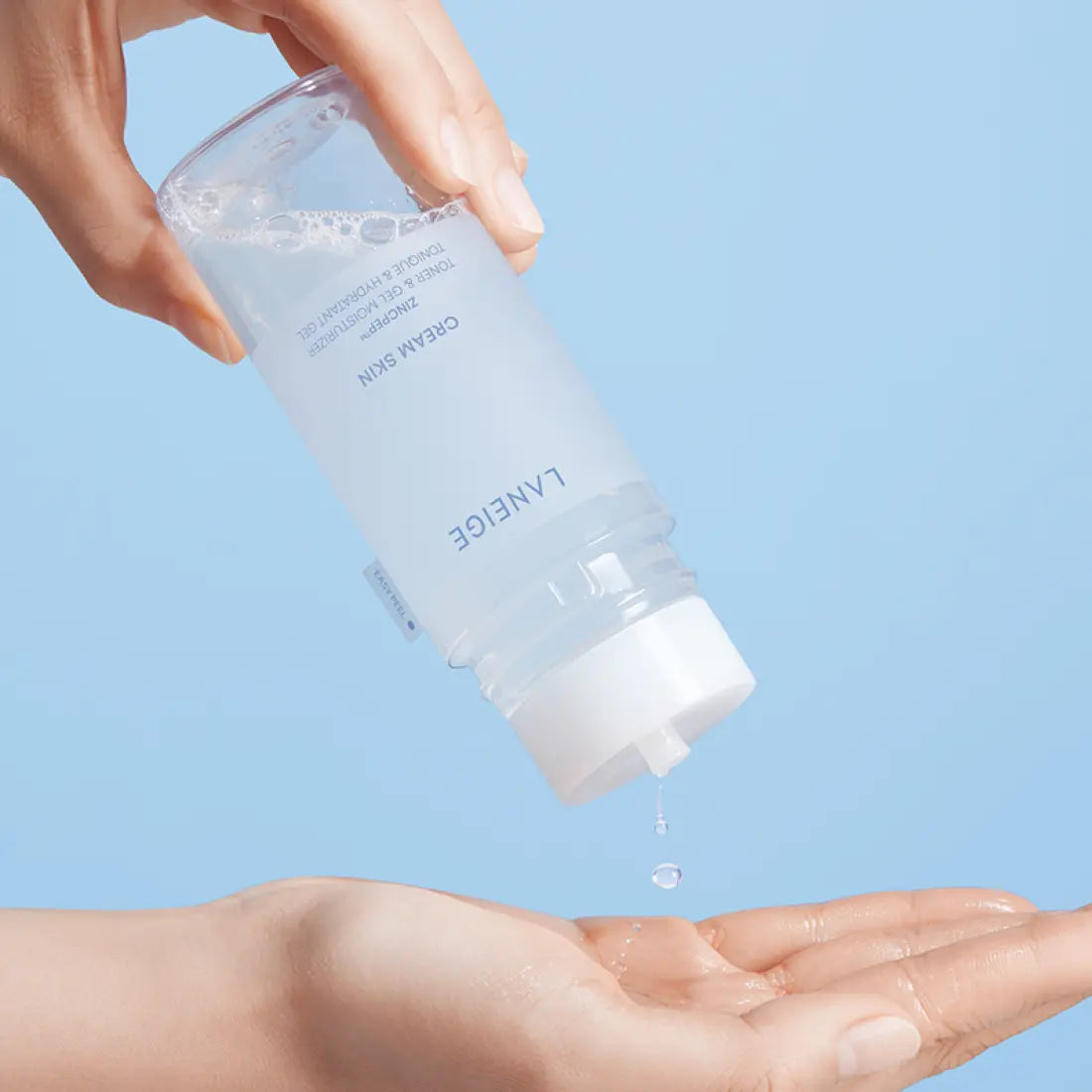 Pouring LANEIGE NEW Gel Cream Skin 170ml into hand with blue background.
