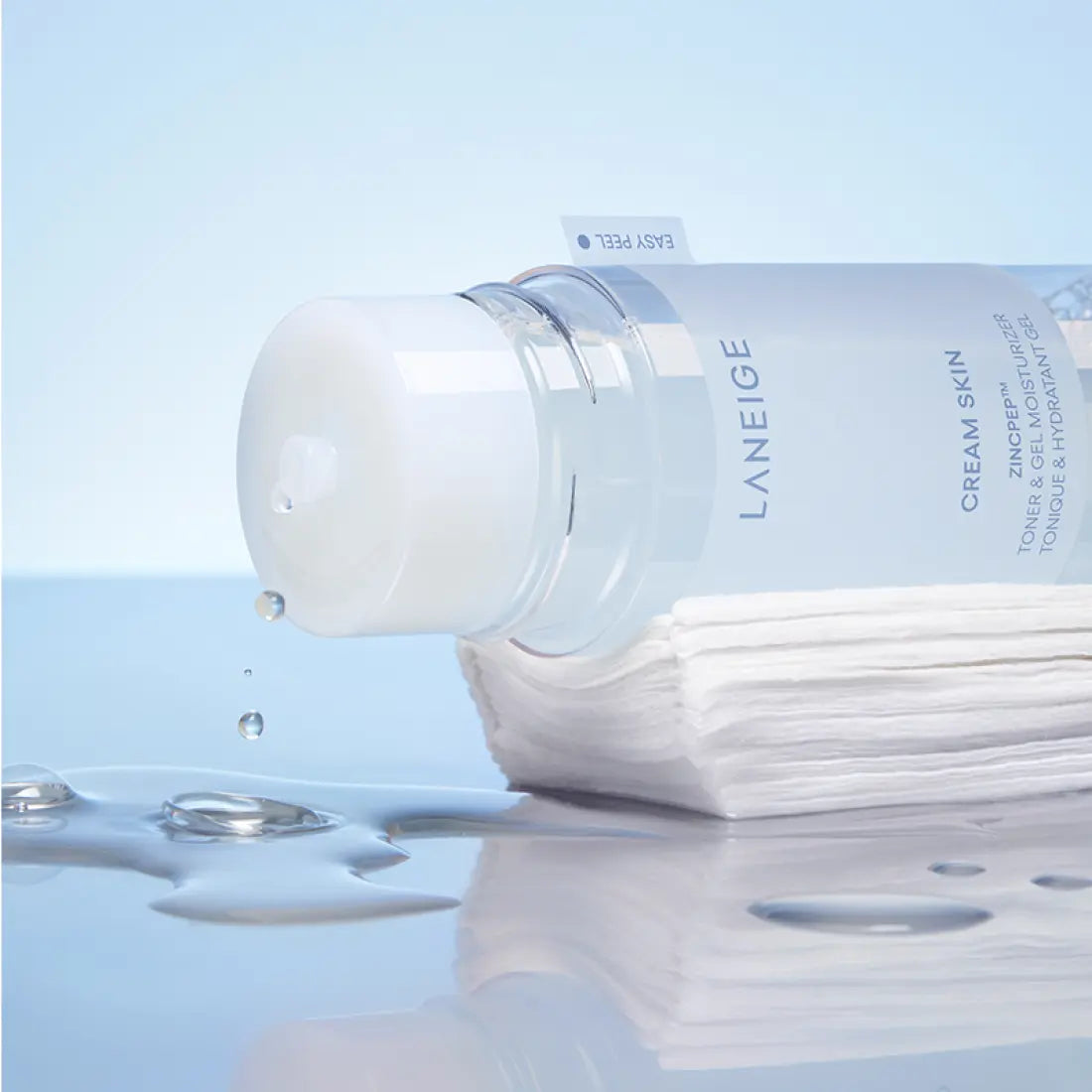 LANEIGE NEW Gel Cream Skin 170ml bottle with drops, showcasing its hydrating texture on a stack of cotton pads, perfect for skincare.