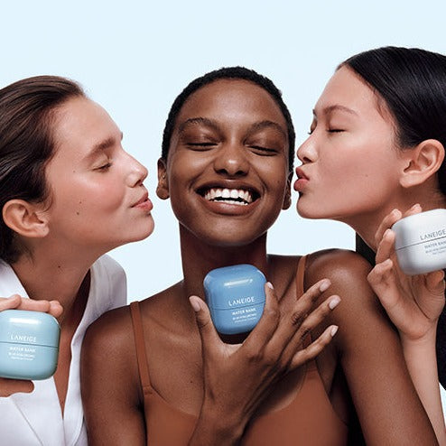 Three women smiling while holding LANEIGE Water Bank Blue Hyaluronic Cream 50ml jars, showcasing radiant skin.