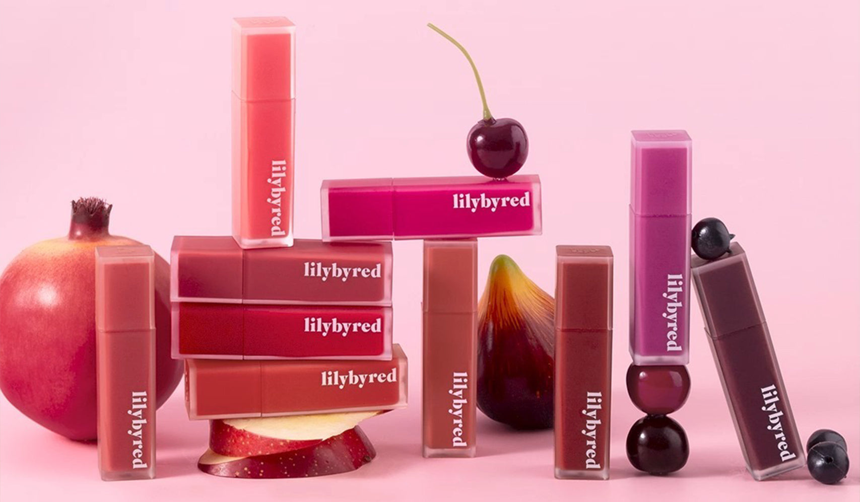 Lilybyred lipstick collection displayed with fresh fruits on a pink background