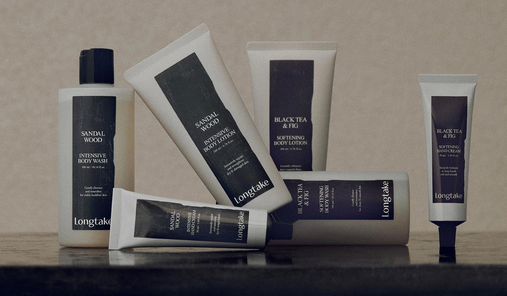 Collection of Longtake skincare products featuring sandalwood and black tea fig body lotions, displayed on a smooth surface.