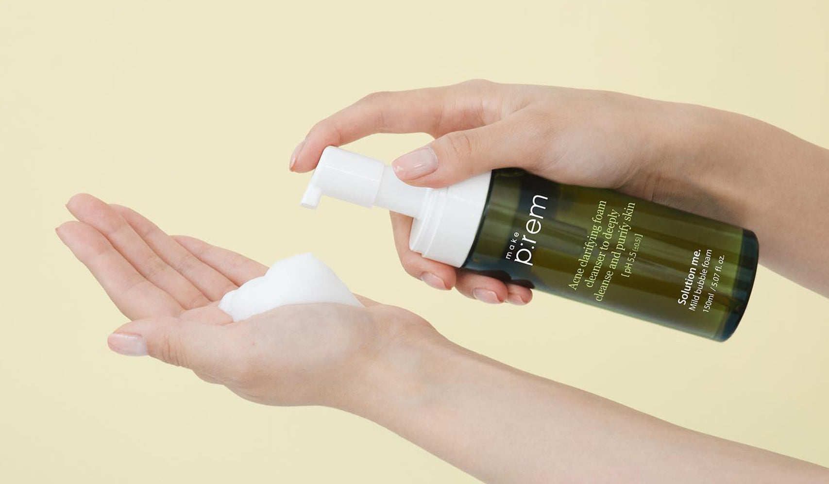 Person dispensing foaming skin cleanser from a green bottle onto their hand, skincare routine