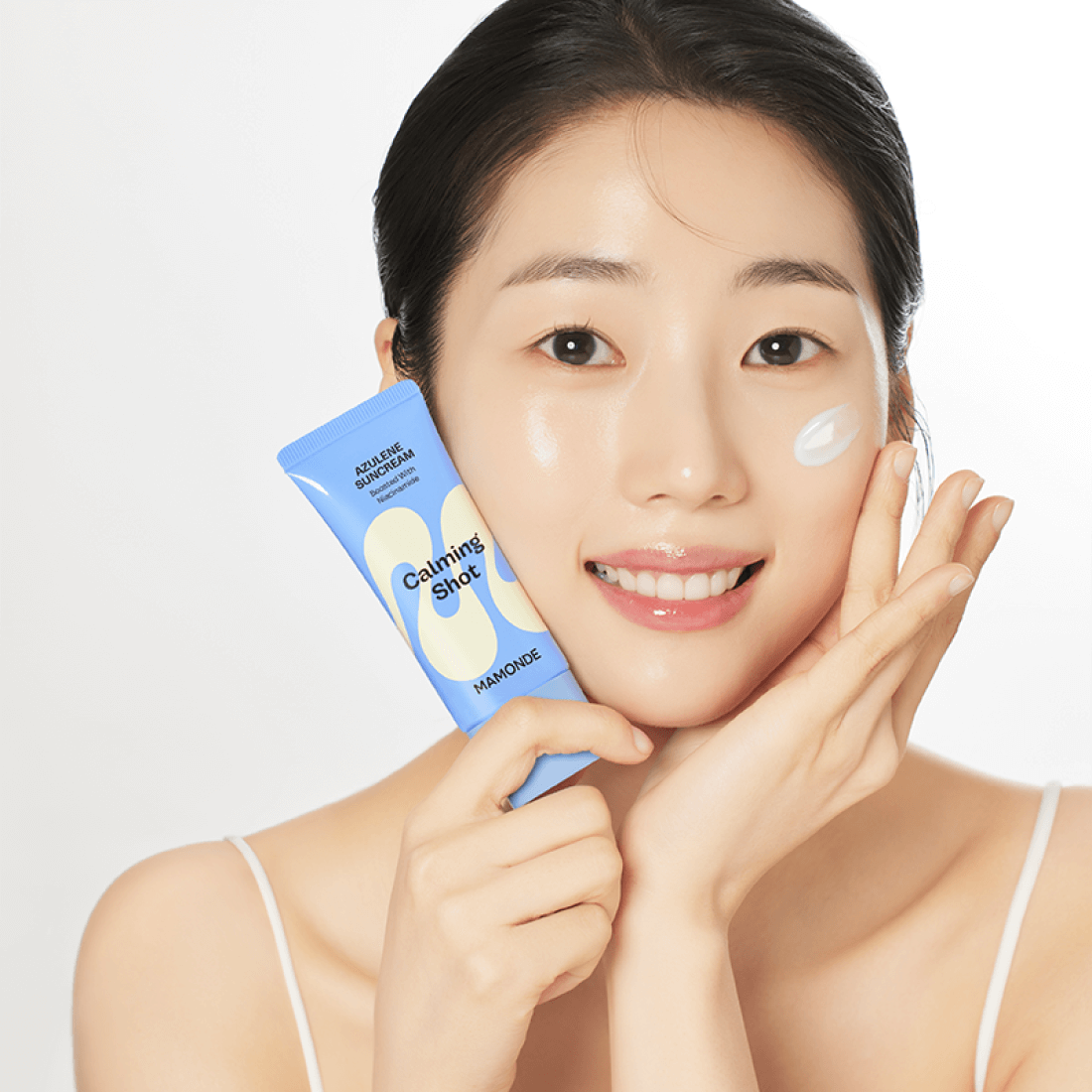 Woman applying MAMONDE Calming Shot Azulene Sun Cream SPF50+PA++++ 35ml with glowing skin