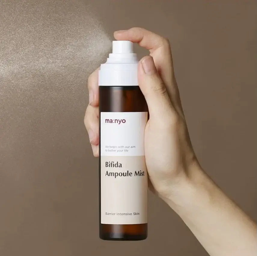 Person holding MANYO Bifida Ampoule Mist 120ml spray bottle against a brown background
