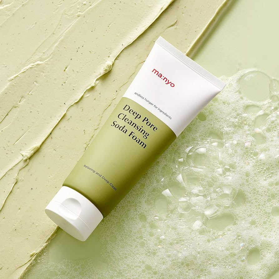 MANYO Deep Pore Cleansing Soda Foam 150ml tube lying on a textured green surface with bubbles around it