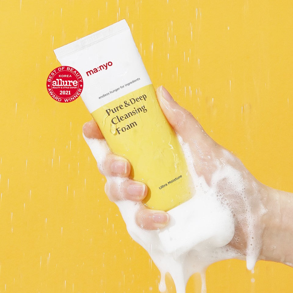 Hand holding MA:NYO Pure & Deep Cleansing Foam 200ml with foam against a yellow background, highlighting skincare product packaging.