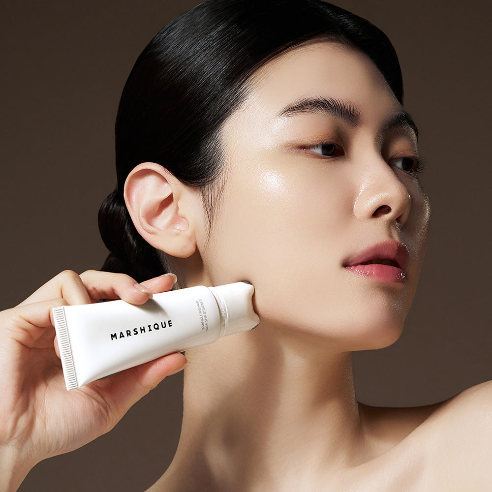 Woman using MARSHIQUE Wrinkle Repair Guasha Essence 45ml for skincare routine.