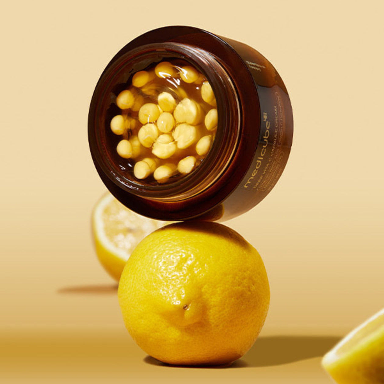 Open jar of MEDICUBE Deep Vita C Capsule Cream 55g with lemons in the background, showcasing skincare product ingredients.