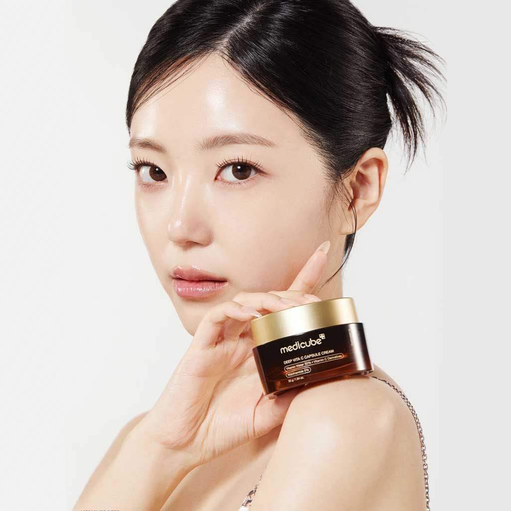 Woman holding MEDICUBE Deep Vita C Capsule Cream 55g, showcasing the product's packaging.