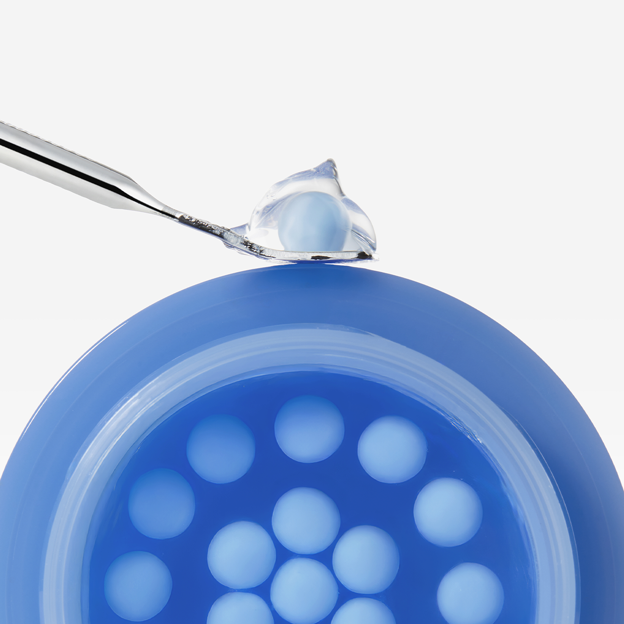 Close-up of MEDICUBE Hyaluronic Moisturizing Capsule Cream 55g showing the cream and capsules in a blue container with a scoop.