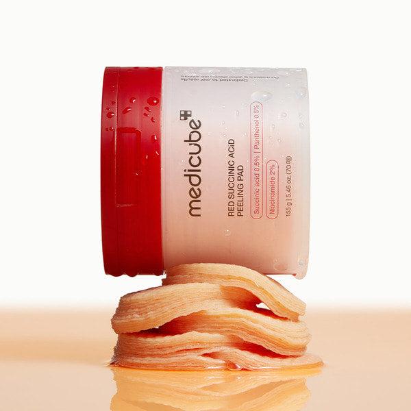 MEDICUBE Red Succinic Acid Peeling Pads 70p 155g on a stack of pads, showcasing skincare product.