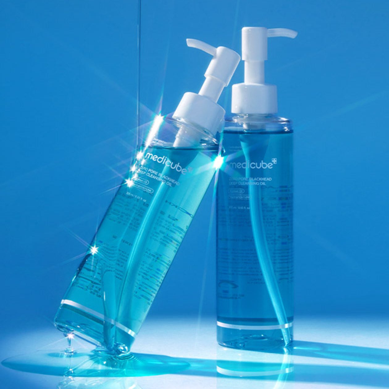 Two bottles of MEDICUBE Zero Pore Blackhead Deep Cleansing Oil 205ml with a vibrant blue background.