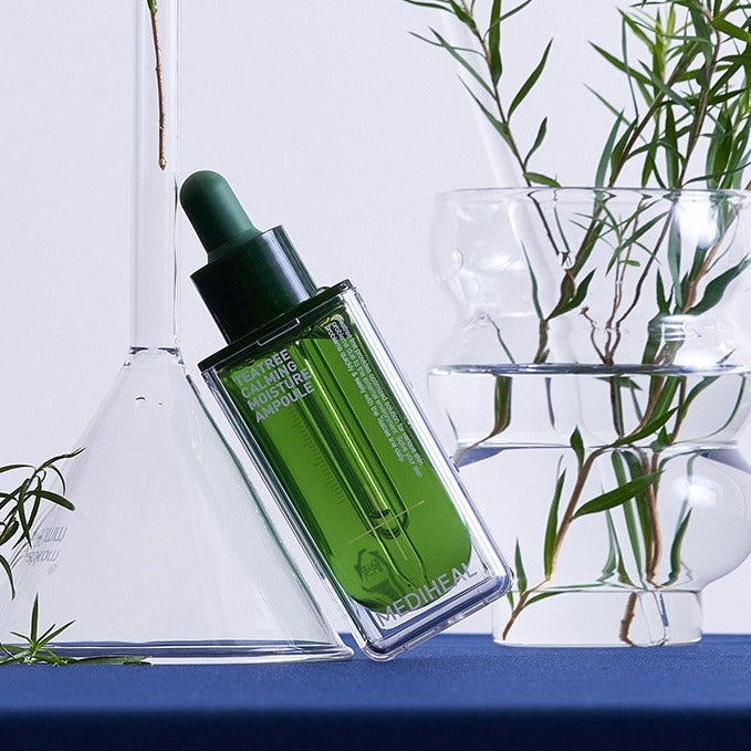 MEDIHEAL Teatree Calming Moisture Ampoule 50ml bottle with green liquid on display with plants