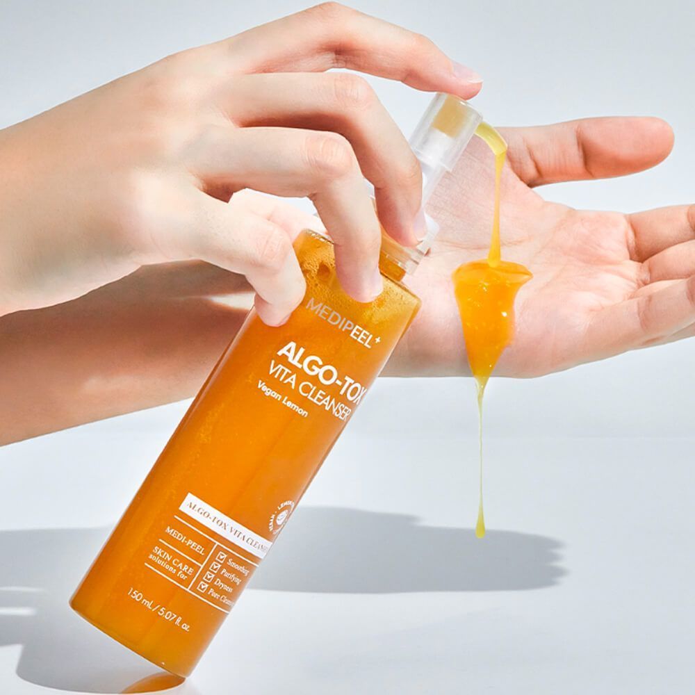 Hand applying MEDIPEEL Algo Tox Vita Cleanser 150ml to skin, showing texture and consistency of the skincare product.