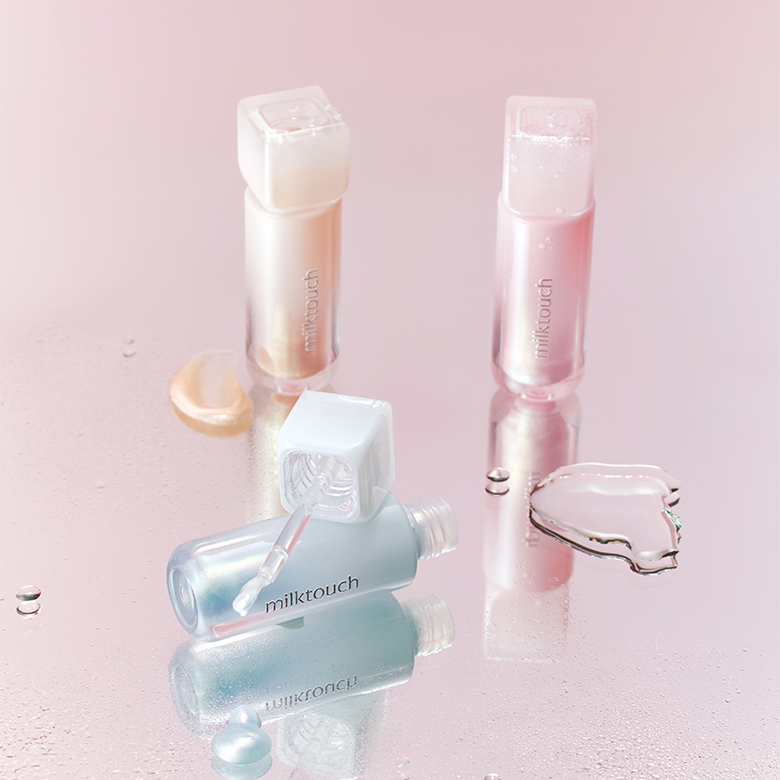 MILK TOUCH Dew Stain Sheer Aurora Gloss in pink and clear shades on reflective surface, open bottle showcasing its applicator.