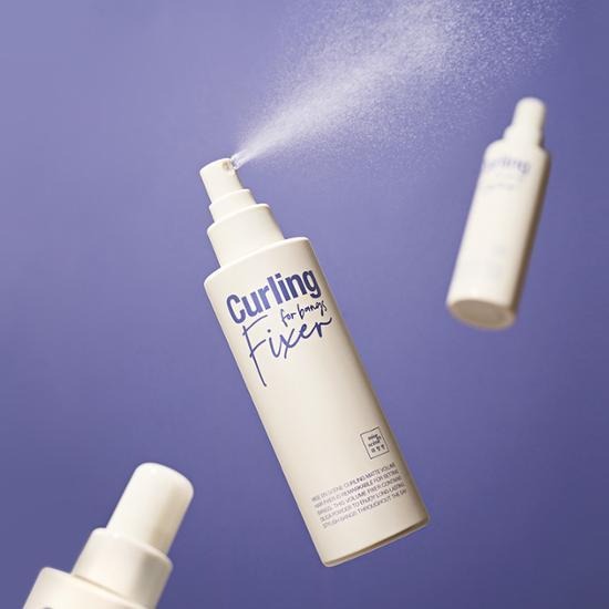 MISE EN SCENE Curling Matte Volume Hair Fixer 200Ml spray bottle on purple background showing product use in action.