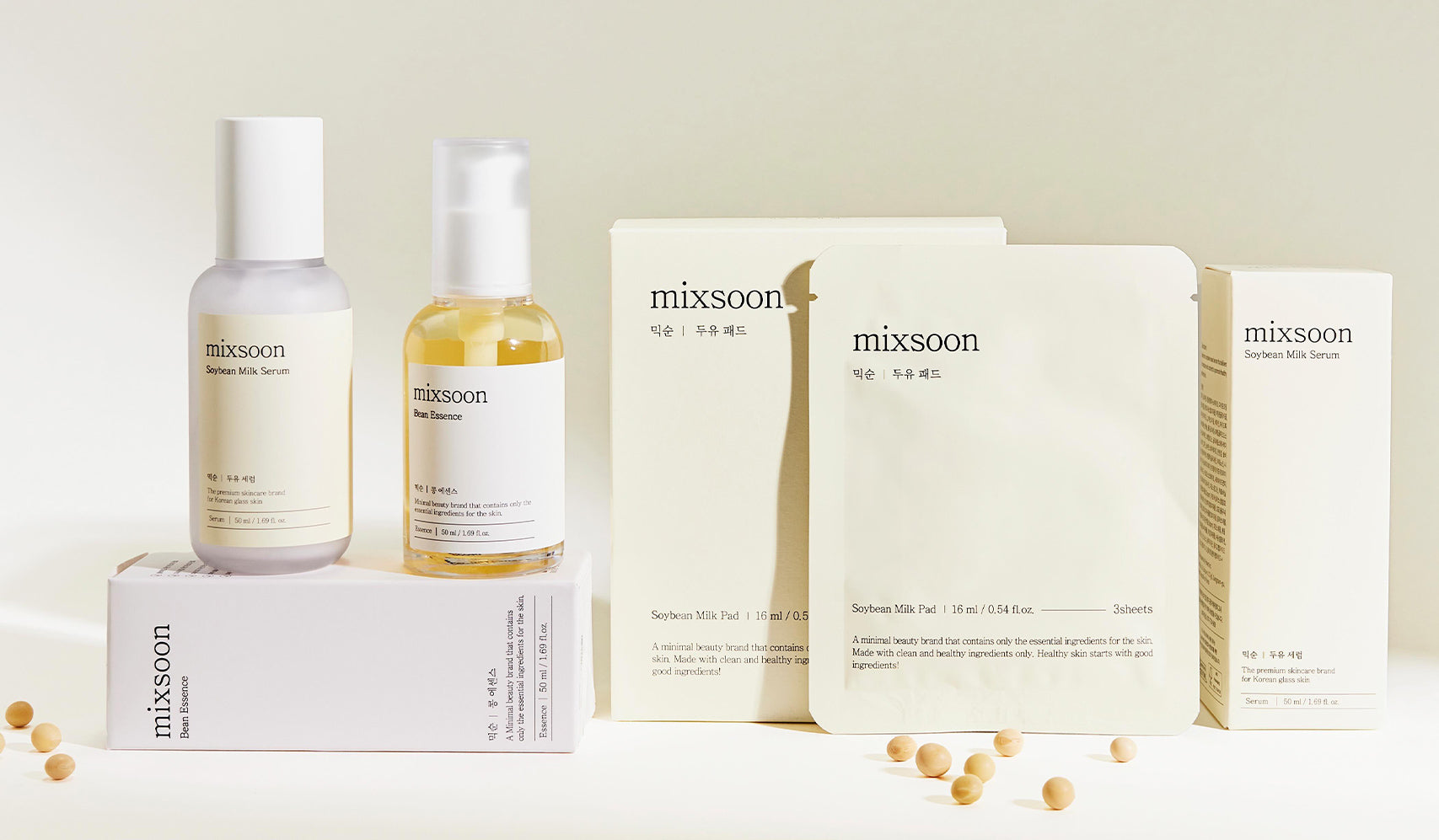 Mixsoon skincare products including serum, toner, and mask displayed with packaging on a soft beige background, alongside soybeans.