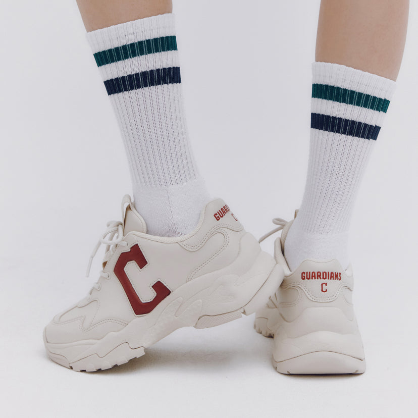 Person wearing MLB Bigball CHUNKY Window Cleaveland Gardians sneakers with striped socks, showcasing sports footwear design.