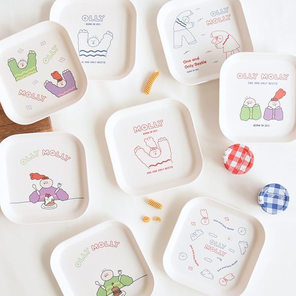 Multiple MONOLIKE Olly Molly Trays with cute designs displayed on a table with small checkered jars and pasta pieces.
