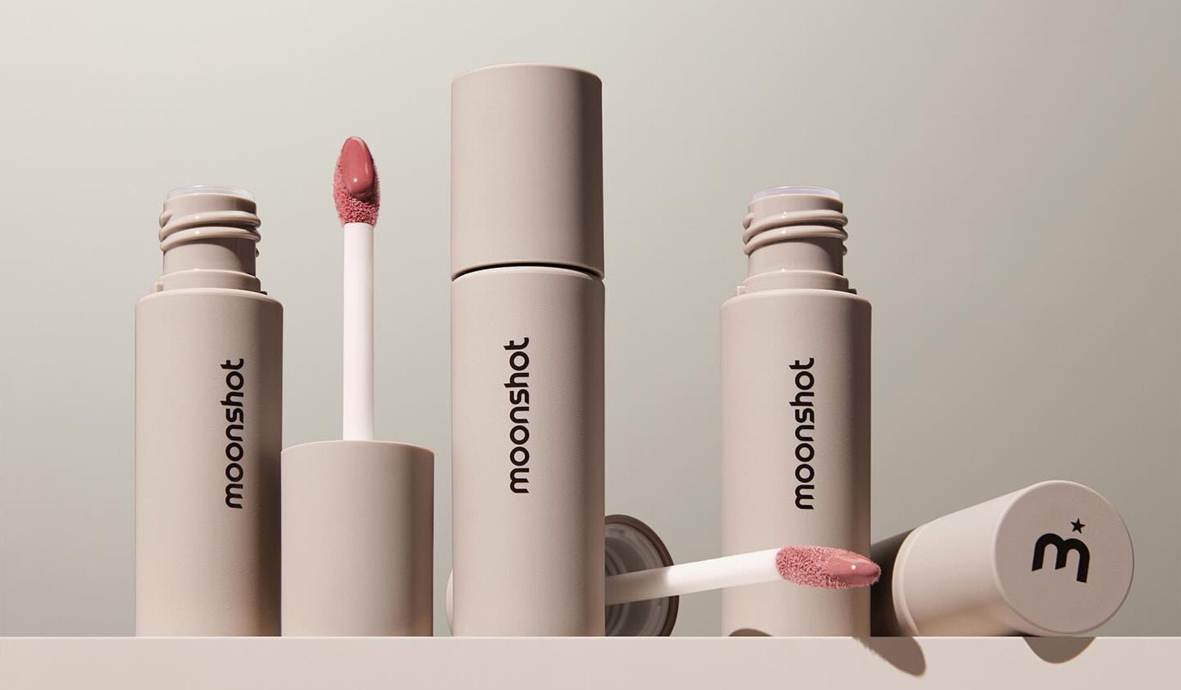 Moonshot lip products showcasing sleek design and applicators with pink lip tint and branding.