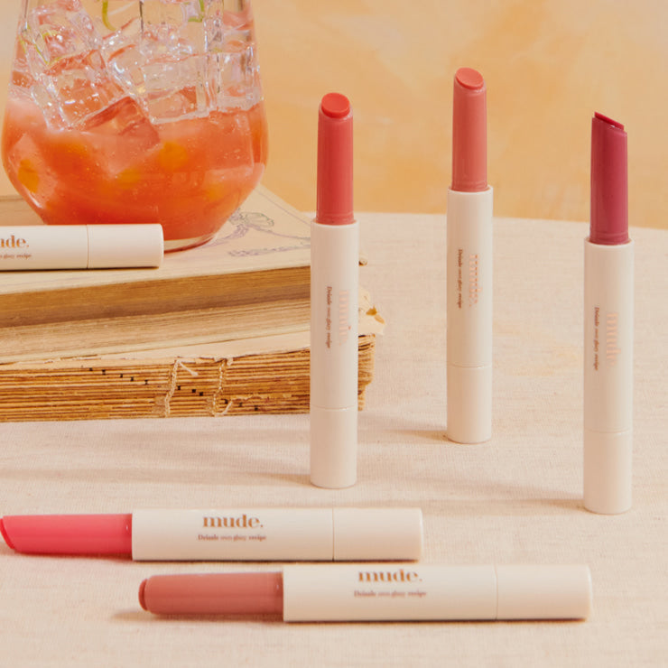 MUDE Drizzle Night lipsticks on display with a cocktail in the background