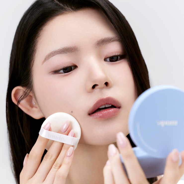 Woman applying MUDE Settingn Powder Patch with a compact mirror.