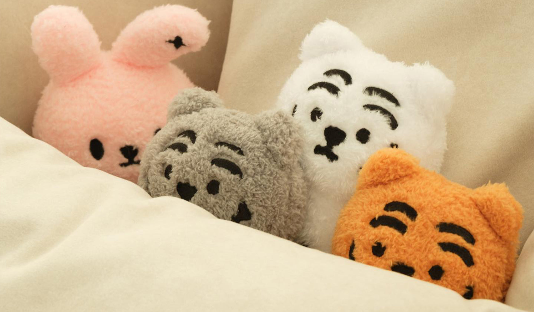 Plush animal toys including a rabbit and three bears lying on a bed.