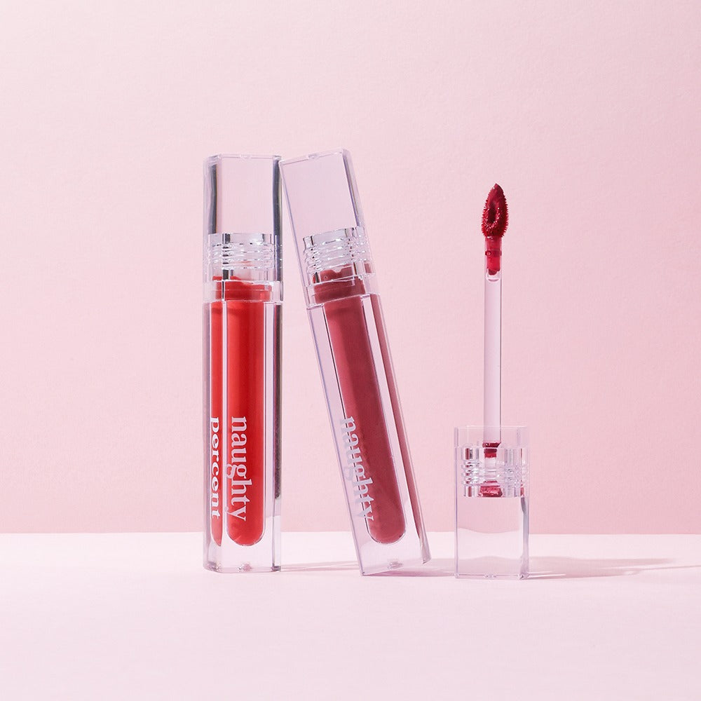 NAUGHTY PERCENT Matte Bloom Tint in two open transparent tubes on a light pink background.