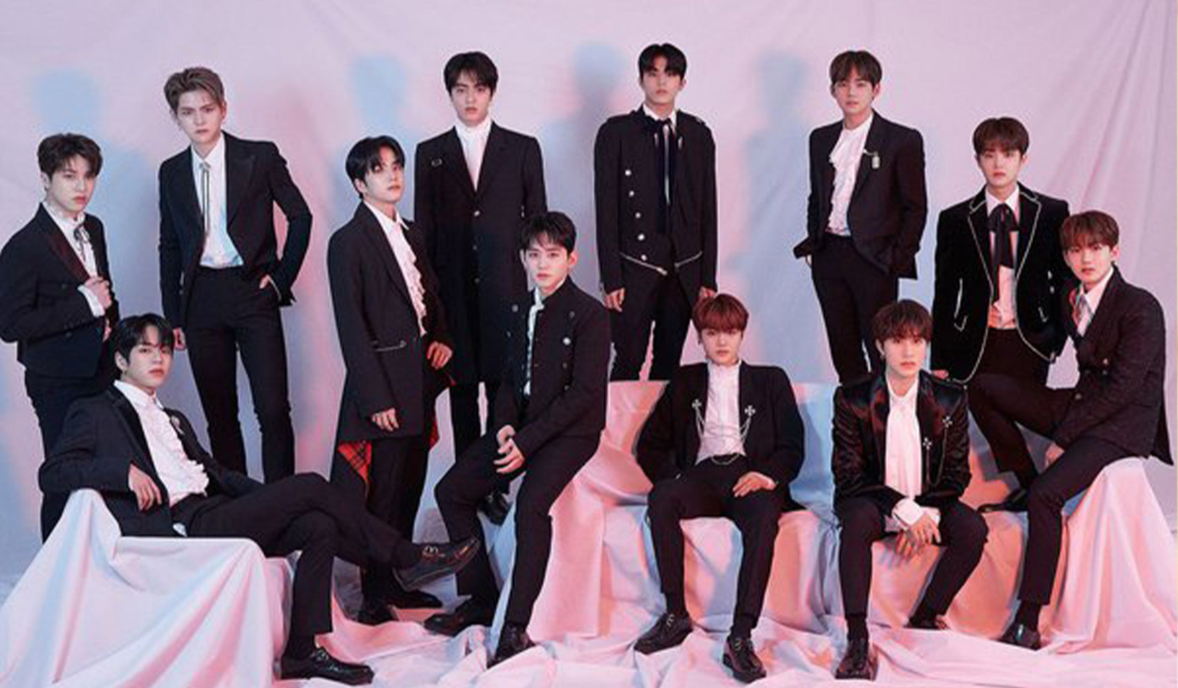 Group of twelve men in formal suits posing in front of a curtain backdrop