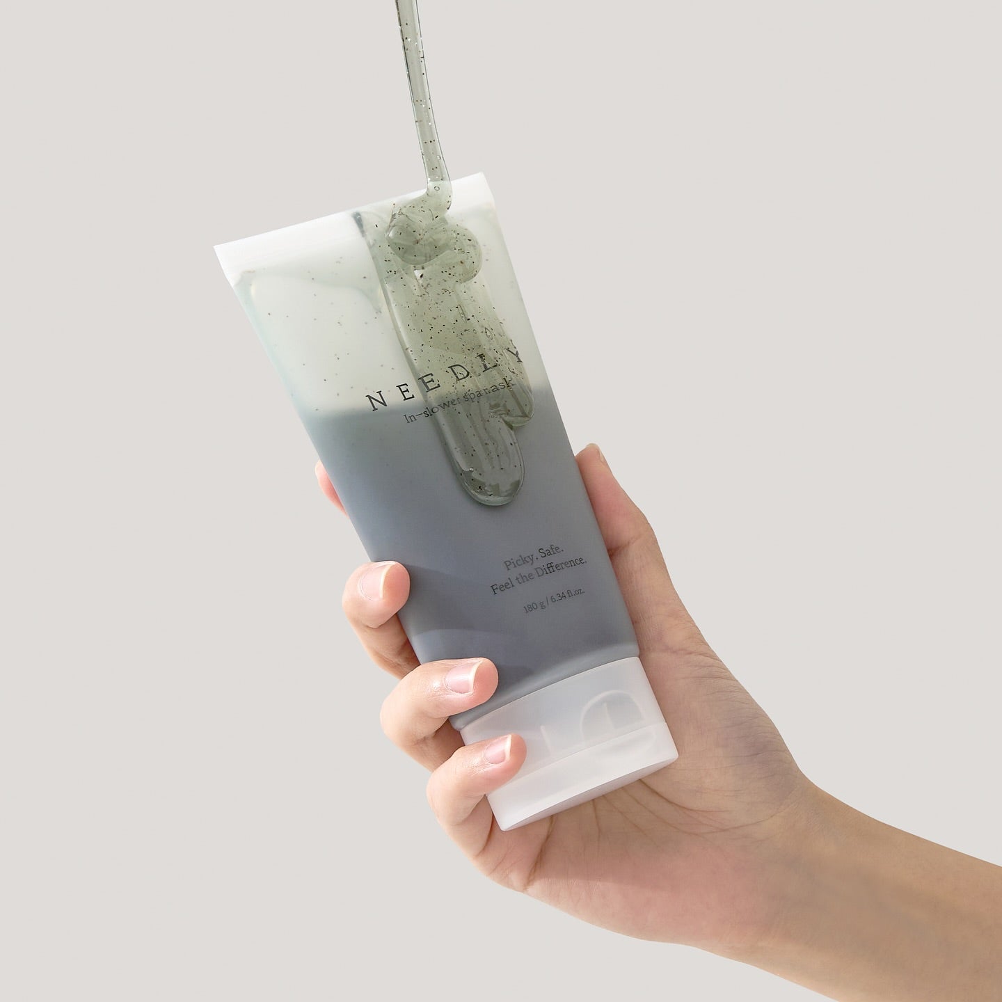 Hand holding a tube of NEEDLY Ishower Spa Mask 180g against a neutral background.