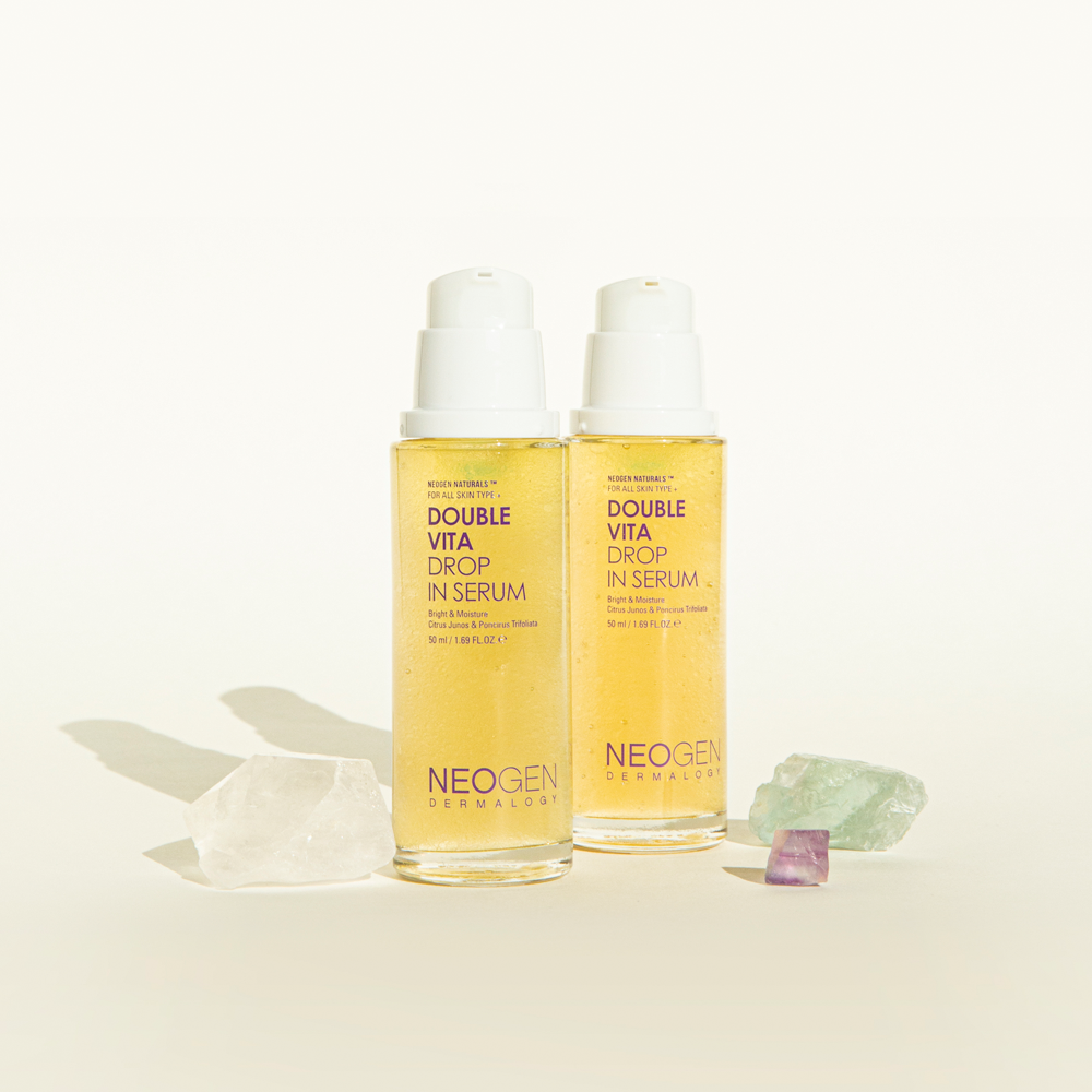 Two bottles of NEOGEN Double Vita Drop in Serum 50ml with gemstones, showcasing skincare product.