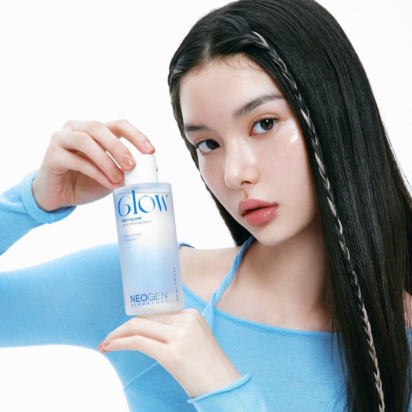 Person holding NEOGEN Next Glow Pore Refining Toner 210ml demonstrating skincare application in blue attire.