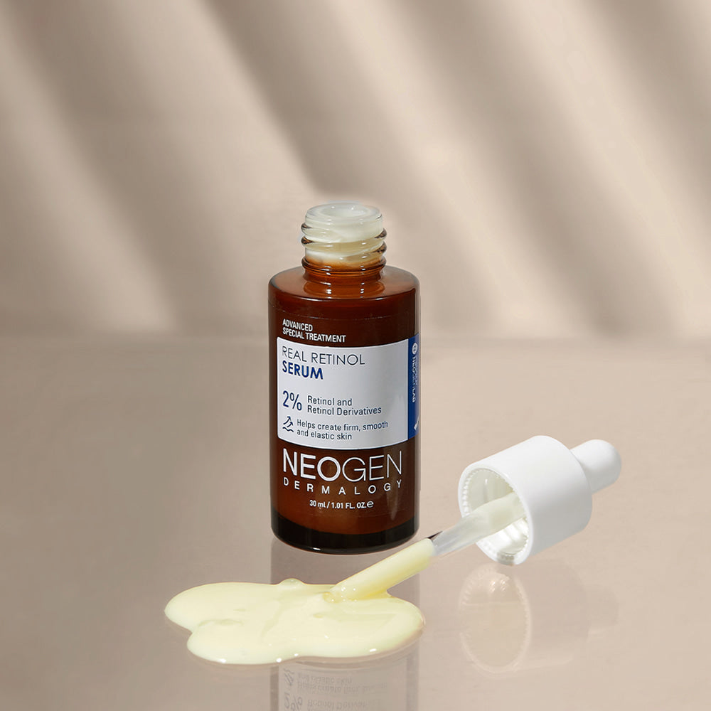 NEOGEN Real Retinol Serum 30ml with dropper and spilled serum on beige background.