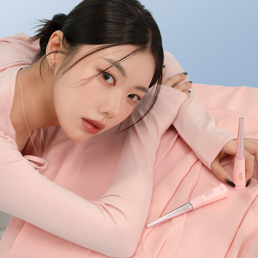 Woman posing with NEOGEN Slim Metal Mascara 6ml on a pink fabric background.