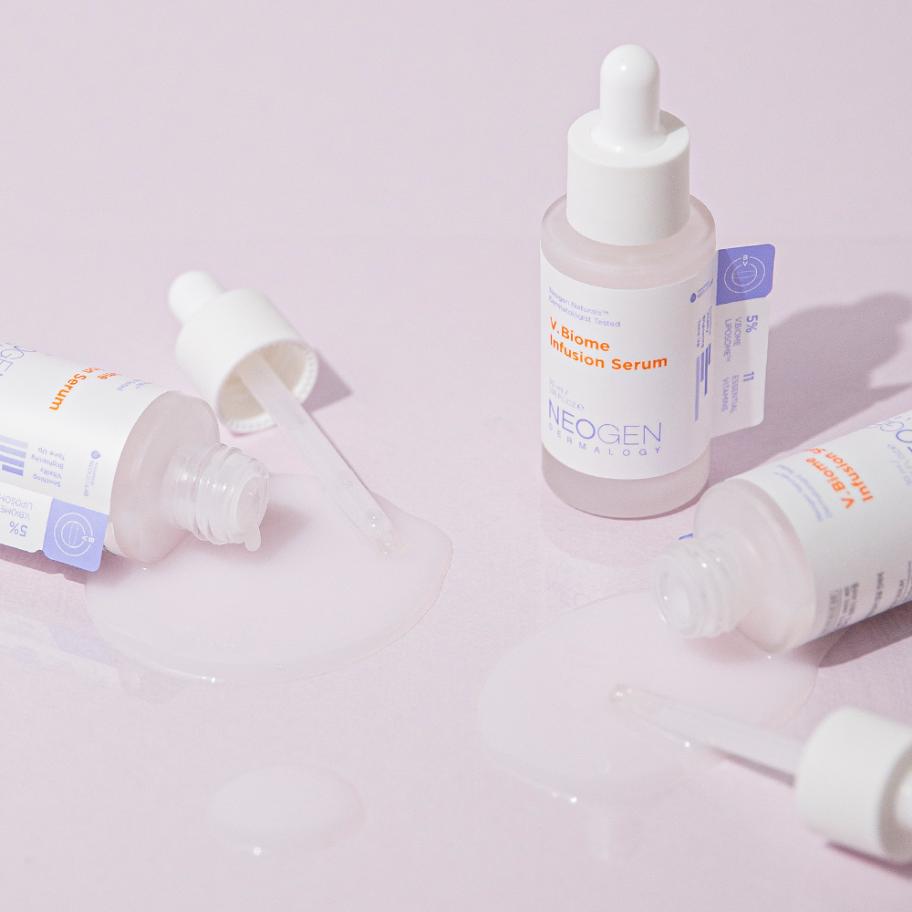 Bottles of NEOGEN V Biome Infusion Serum 30ml with droppers and serum spillage on a pastel surface.