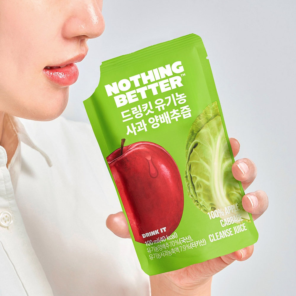 Person holding NOTHING BETTER Drinkit Organic Applr Cabbage Juice 100ml packet with apple and cabbage image on packaging.