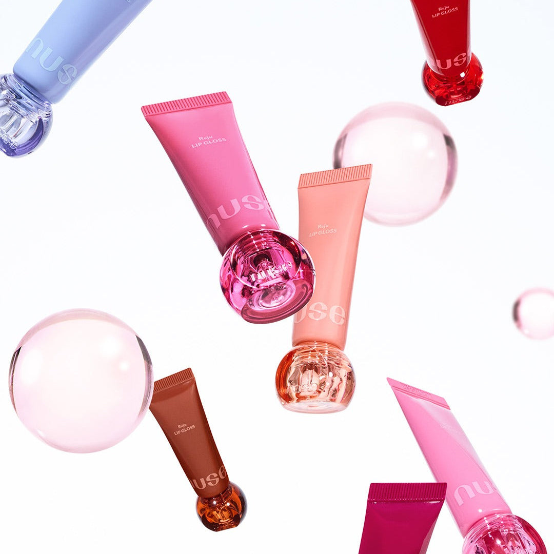 Colorful tubes of NUSE Nuzzle Reju Lip Gloss floating with bubbles on a white background.