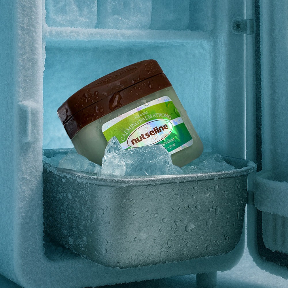 NUTSELINE Cica Nut Calming Balm Strong 50ml jar in freezer surrounded by ice, showcasing cooling effect for calming relief.