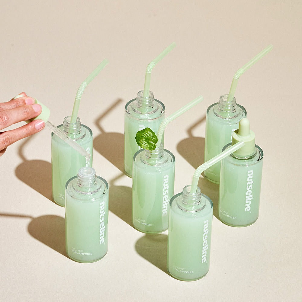 NUTSELINE Cica Nut Hyal Ampoule 90ml bottles with green liquid and pipette on a beige background.