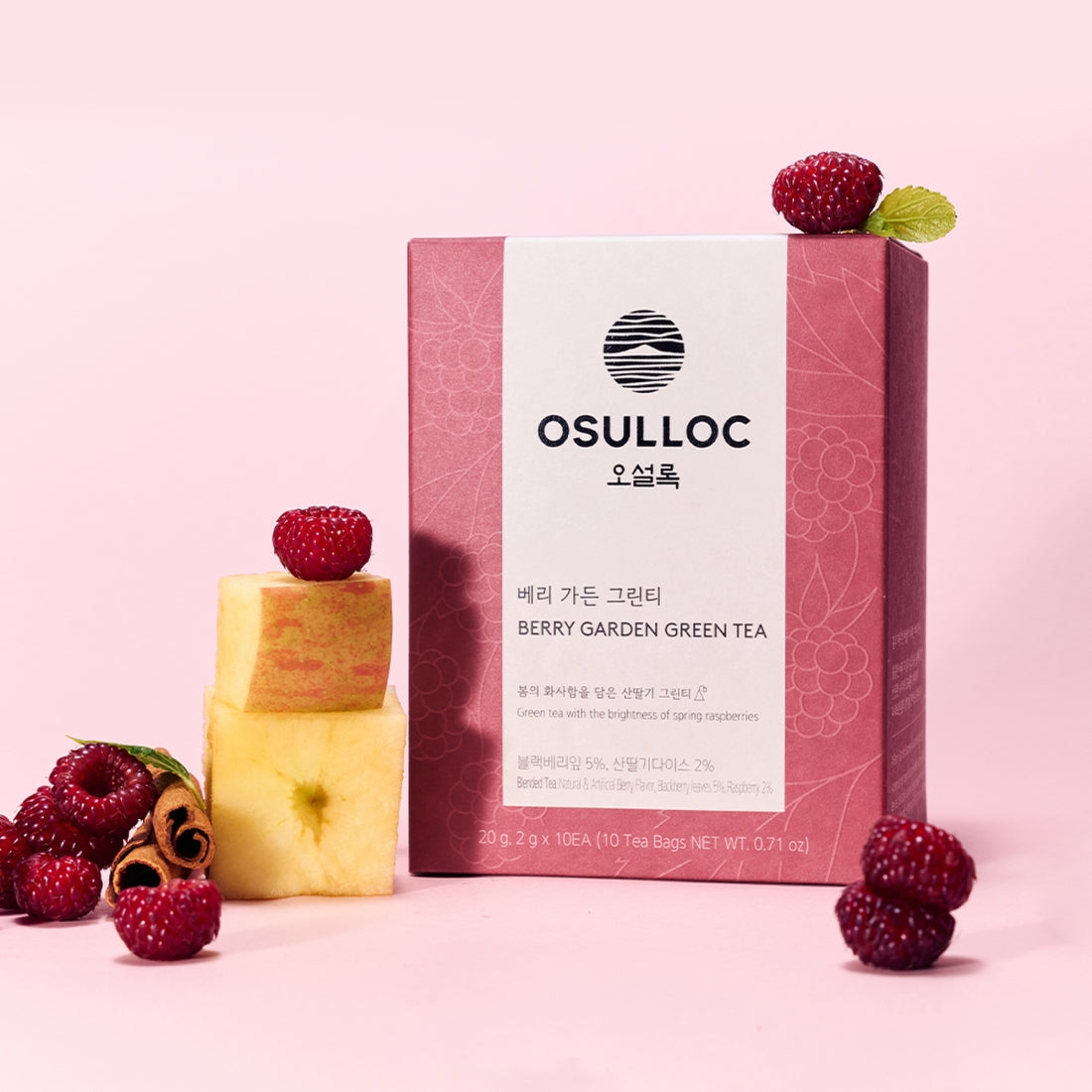 Box of OSULLOC Berry Garden Green Tea 10 P with raspberries and apple slices on a pink background.