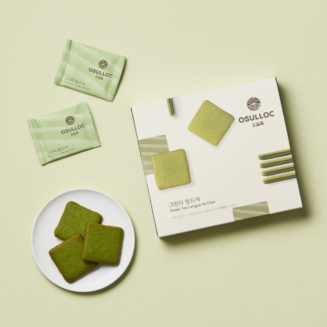 Box and plate of OSULLOC Green Tea Langue de chat 10 p. with individually wrapped cookies on a light green background.