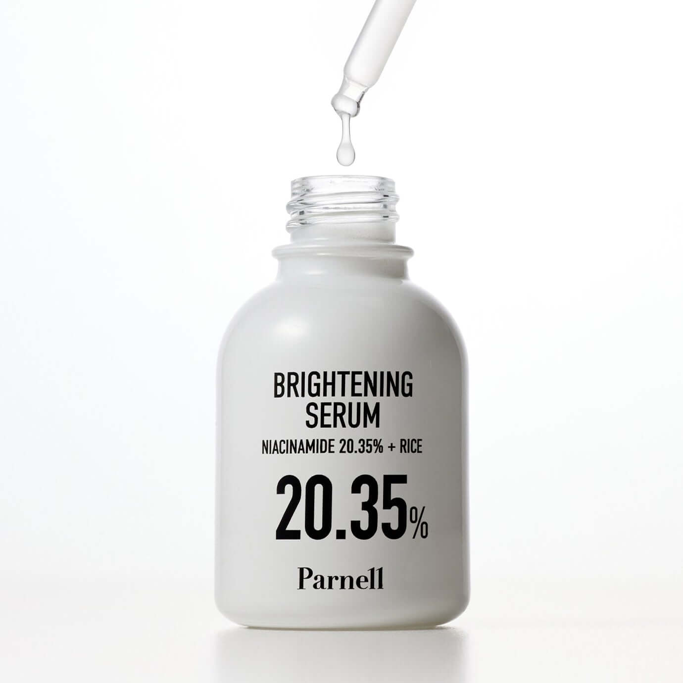 PARNELL Niacinamide 20.35 Rice Brightening Serum 30ml bottle with dropper and clear liquid emerging from it.