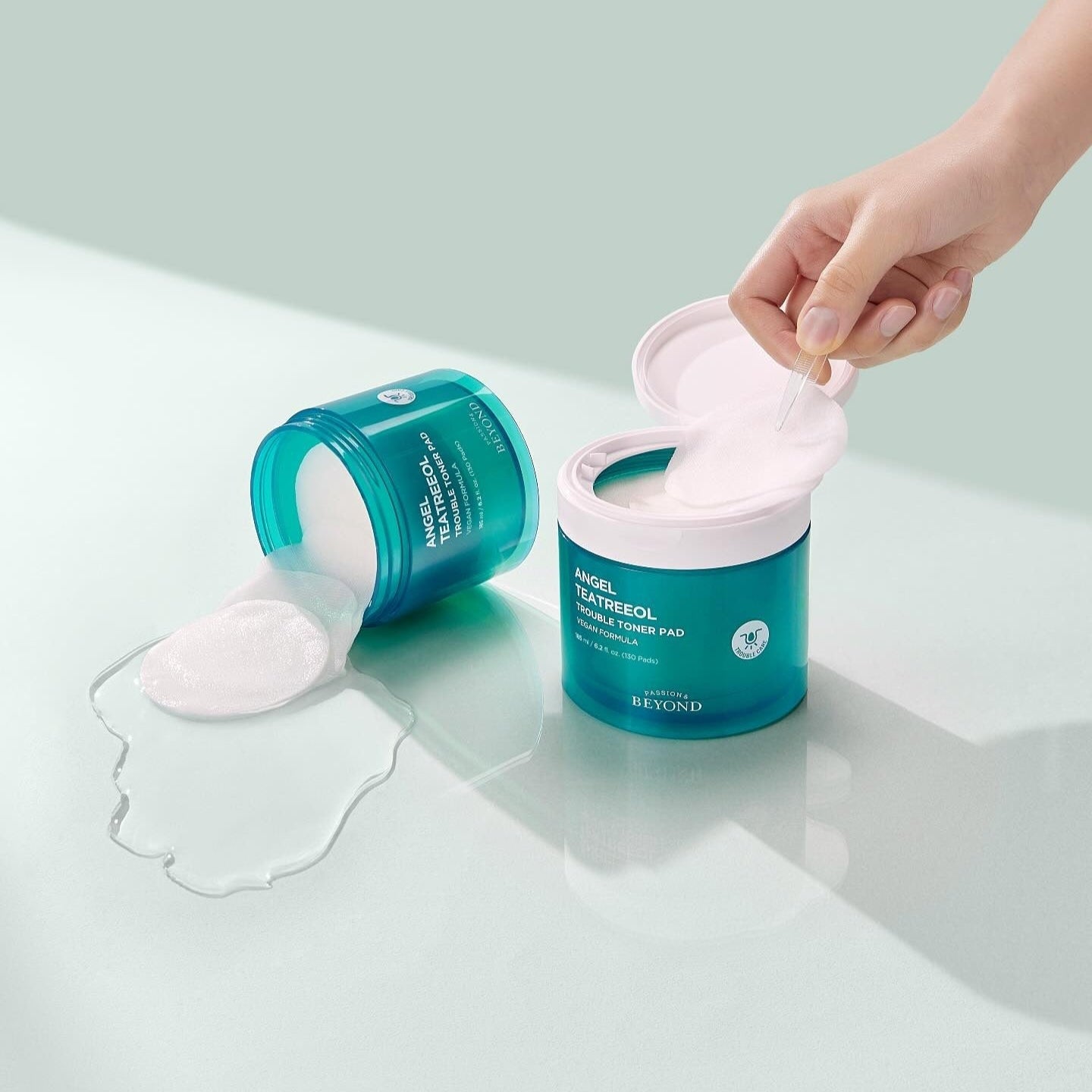 PASSION&BEYOND Angel Tea Tree Trouble Toner Pads 185ml skincare product with open lid and spilled pads on a light surface.