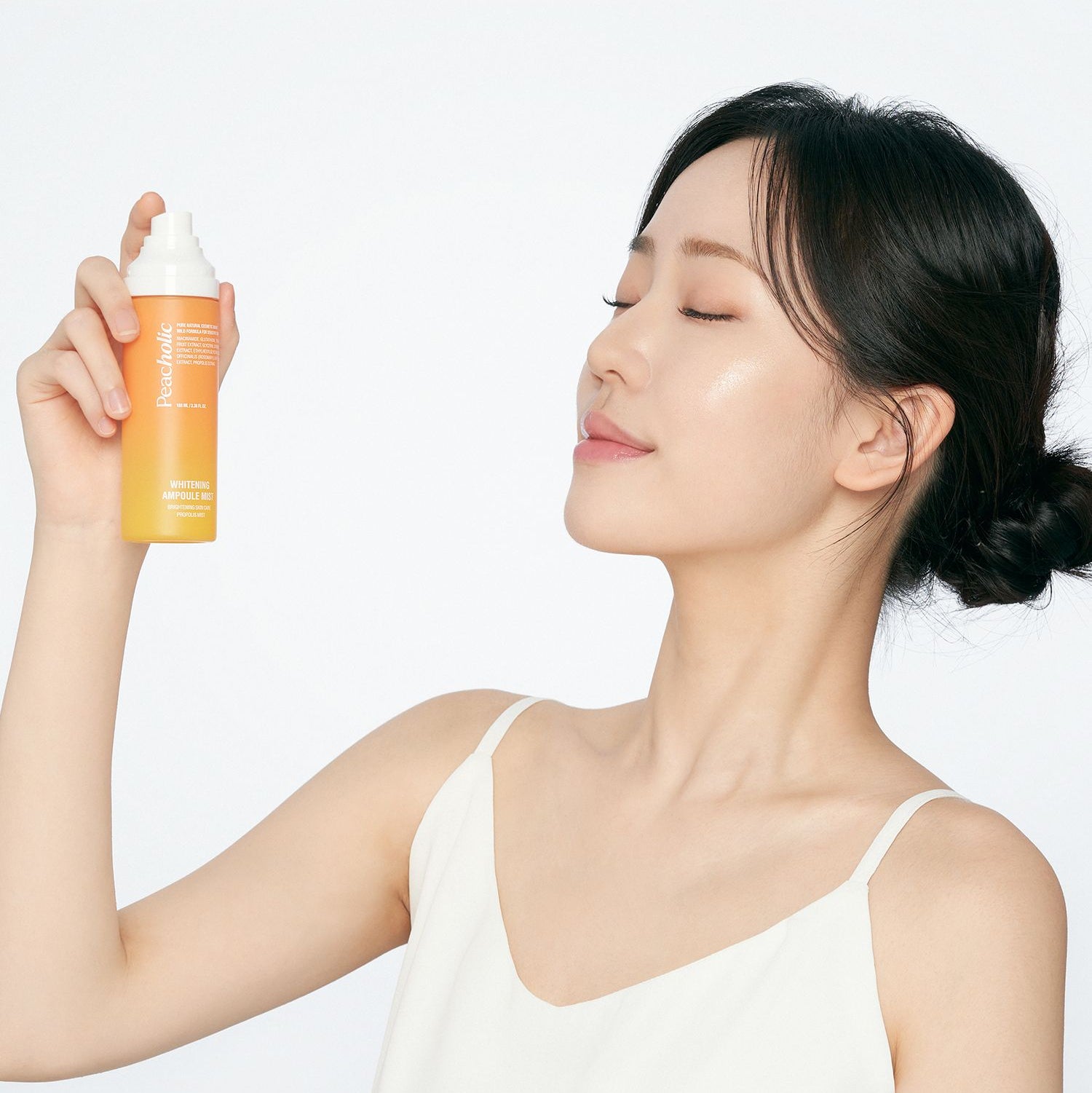 Person using PEACHOLIC Whitening Ampoule Mist 100ml for skin hydration and glow