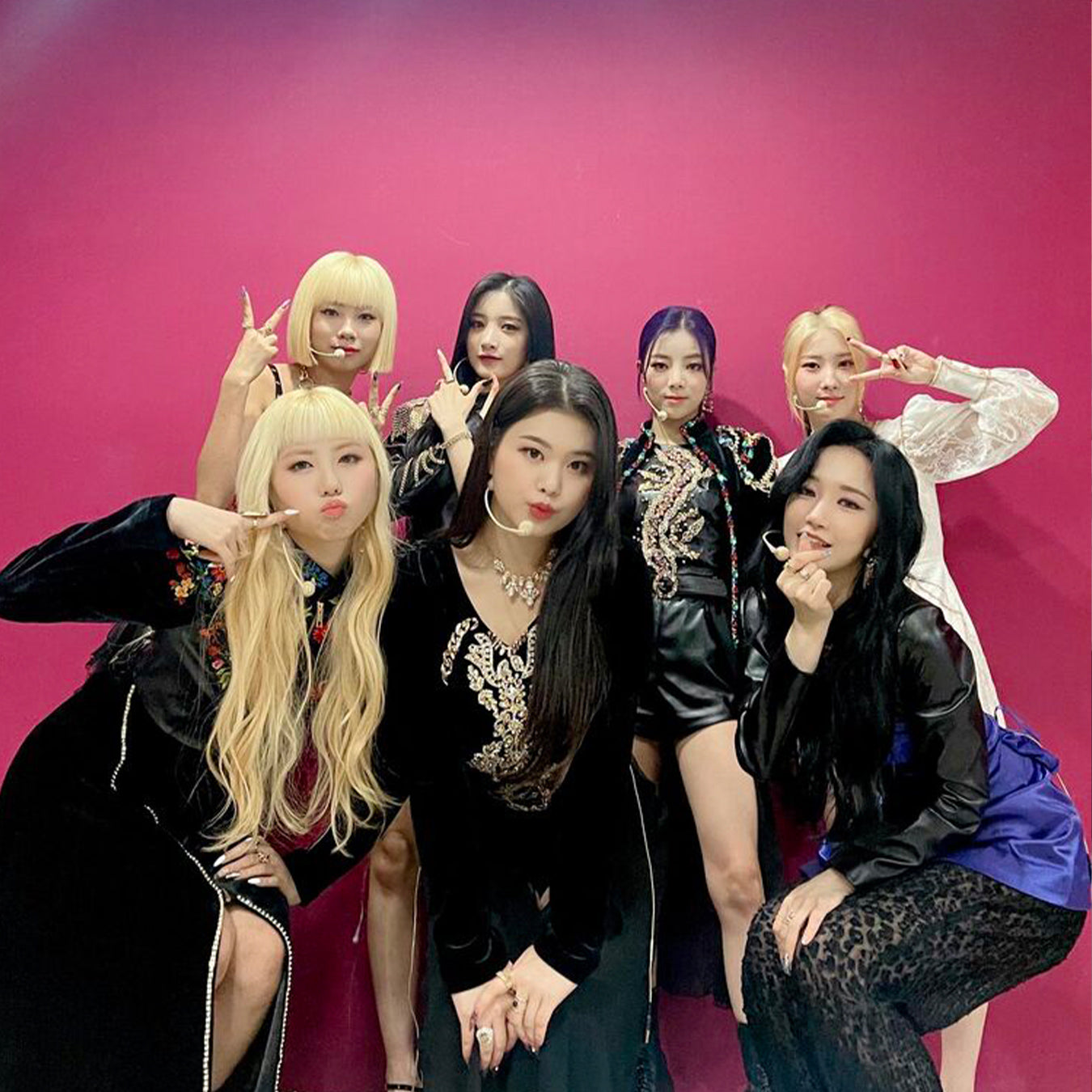Seven women posing stylishly against a vibrant pink background, each with unique outfits and expressive poses.