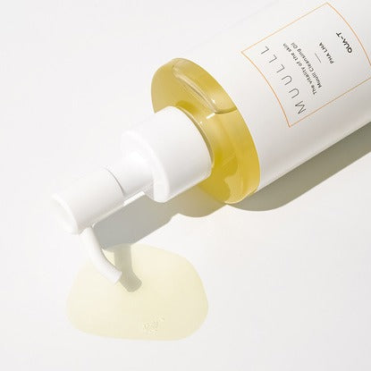 QUA-T Cleansing oil 200ml bottle lying on its side with oil pouring out. High-quality skincare product for gentle cleansing.