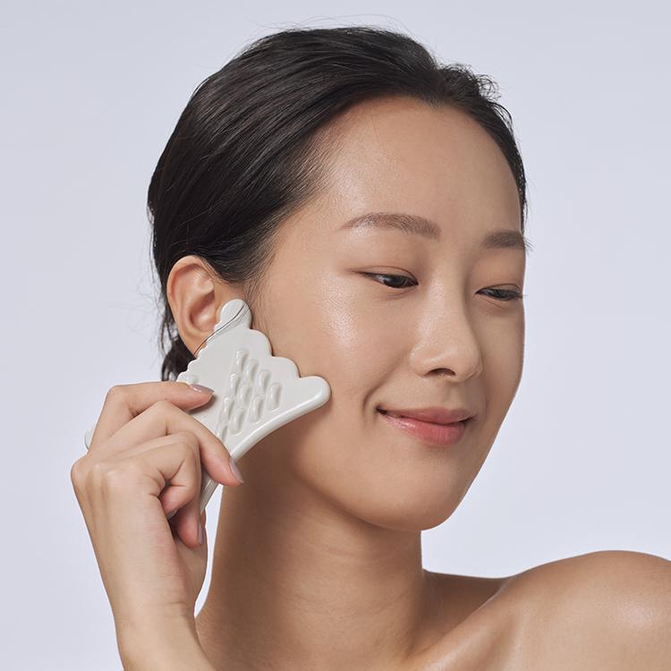 Person using RETURNITY Mini Guasha, showing skincare tool application on facial skin.