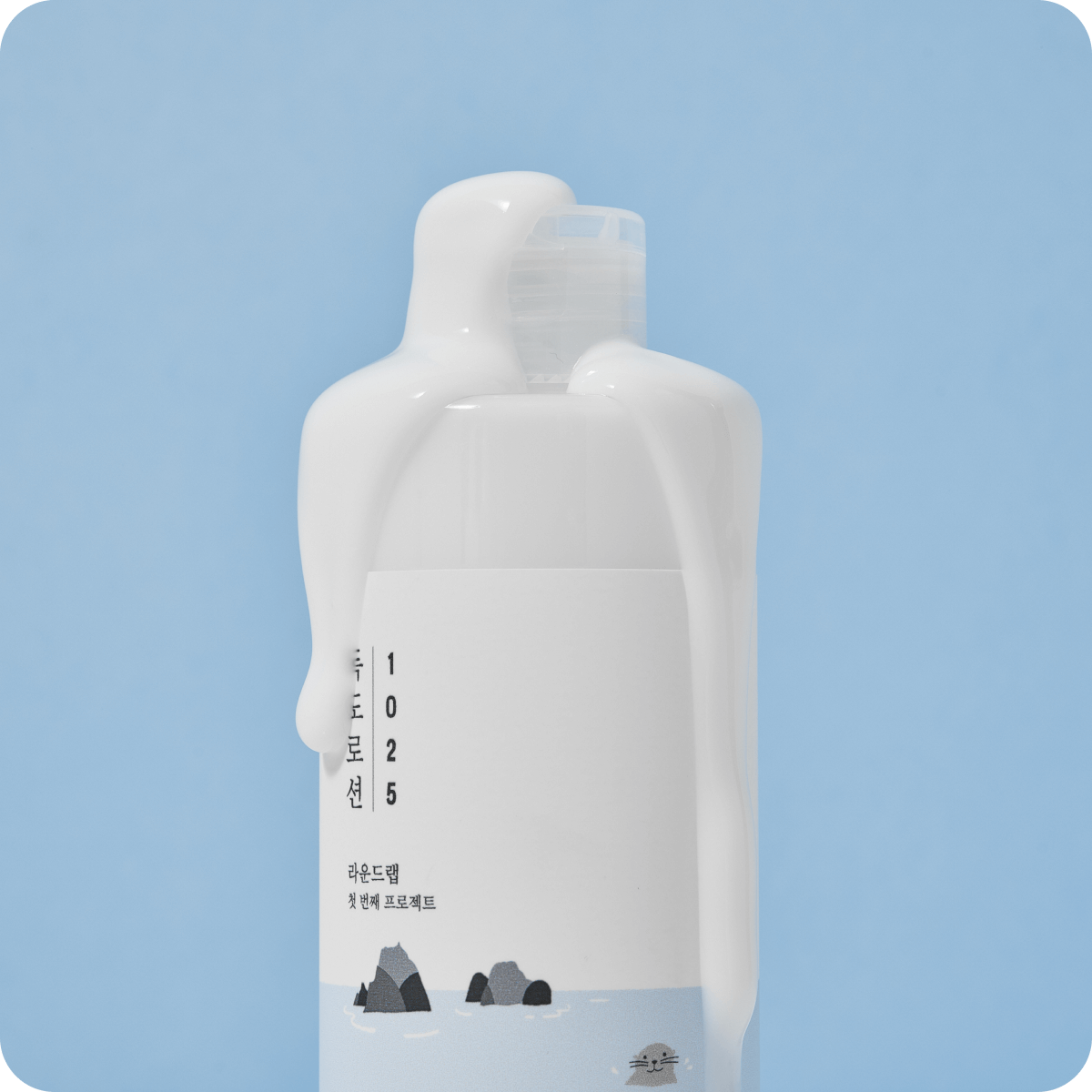 ROUND LAB 1025 Dokdo Lotion 400ml bottle with lotion dripping, against a blue background.