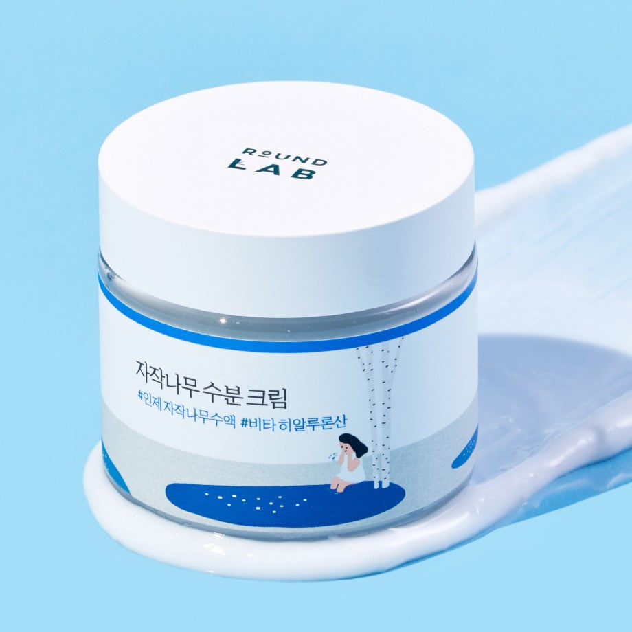ROUND LAB Birch Juice Moisturizing Cream 80ml in a jar on a textured blue background